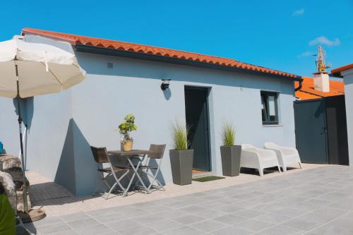 a white house with a table and chairs and an umbrella at 9min Metro to Downtown - couples&kids - free parking in Porto