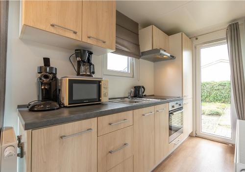 a kitchen with a microwave oven and a sink at Chaletparc Krabbenkreek Zeeland - Chalet 78 in Sint Annaland