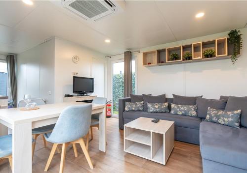 a living room with a couch and a table at Chaletparc Krabbenkreek Zeeland - Chalet 78 in Sint Annaland