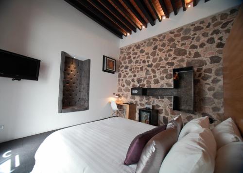 1 dormitorio con cama y pared de piedra en Hotel Boutique MO17, en Querétaro
