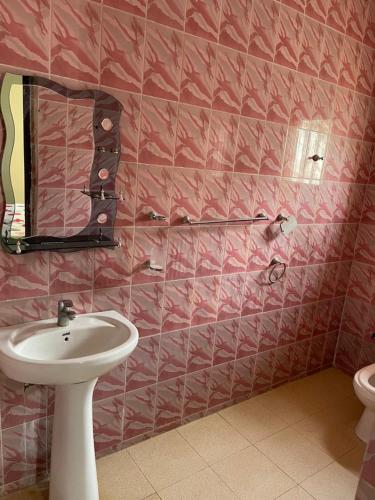 a pink tiled bathroom with a sink and a mirror at Brufut House Close to Brufut Beach in Brufut
