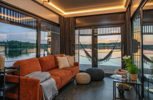 a living room with an orange couch and large windows at Water Hideout - Floating Secret Spot in Mazury in Wojnowo