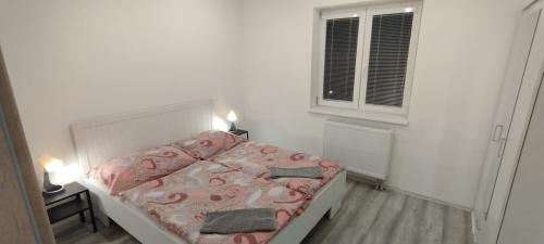 a bedroom with a bed with pink sheets and a window at Apartmán Hortenzie in Mařenice