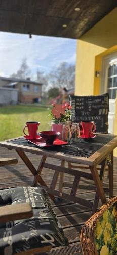 einem Holztisch mit roten Tassen und Platten darauf in der Unterkunft Ferienhaus Wiese und Meer in Zinnowitz