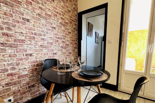 une pièce avec une table et des chaises et un mur de briques dans l'établissement Studio lumineux, à Agen