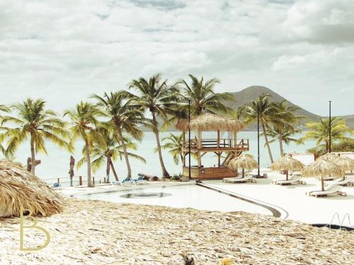 a resort pool with palm trees and a beach at 412 The Diamond Swing in Le Diamant