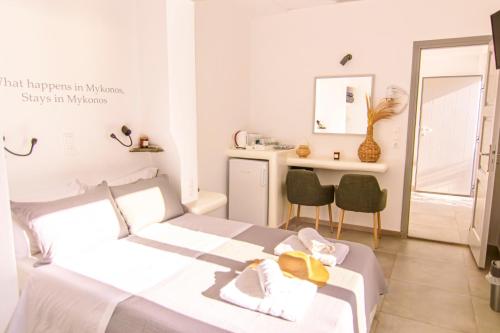 a white bedroom with a bed and a desk at Zisis Pension in Agios Stefanos
