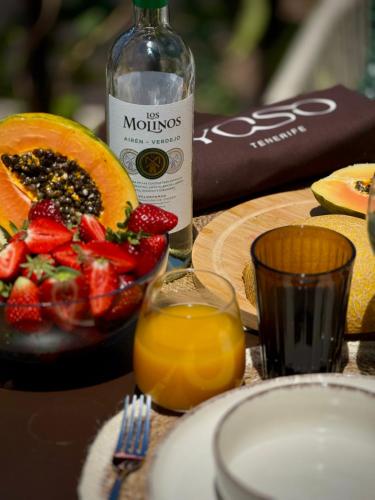 a table with a bottle of wine and a plate of fruit at YOSO Tenerife in Acantilado de los Gigantes