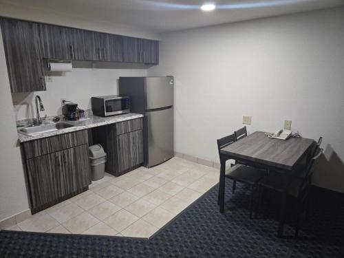 a small kitchen with a table and a refrigerator at Allure Suites of Fort Myers in Fort Myers
