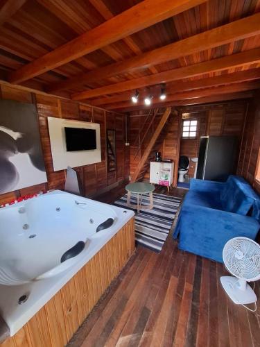 a large tub in a living room with a blue couch at Chalé do Beijo in Nazaré Paulista