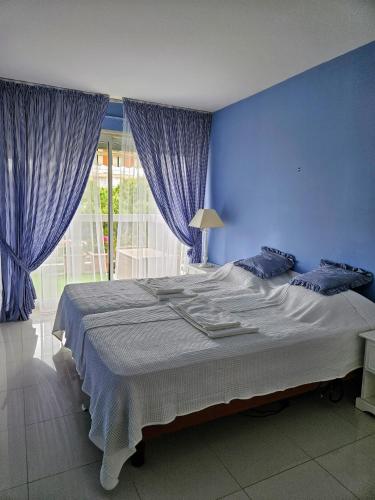 - une chambre bleue avec un grand lit et des rideaux bleus dans l'établissement Appart 2 pièces, Juan les Pins, plage 400 m, parking, à Antibes