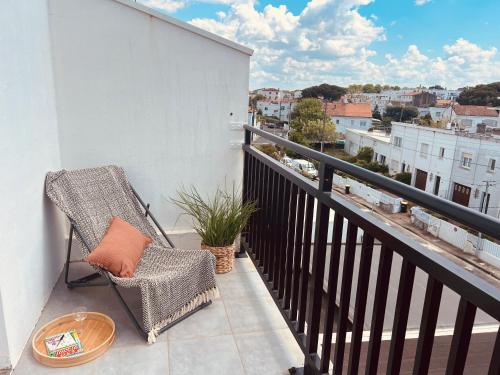une chaise sur un balcon avec vue sur la ville dans l'établissement L'escapade du 3ème - Aperçu mer & Terrasse en Centre-ville, à Royan