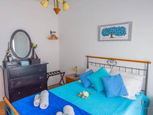 a bedroom with a bed with blue pillows and a mirror at Pátio Privado com Churrasqueira by Férias em Figueira in Figueira da Foz