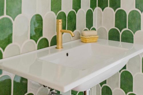 a white sink in a bathroom with green and white tiles at La casa di rovere in Lugo