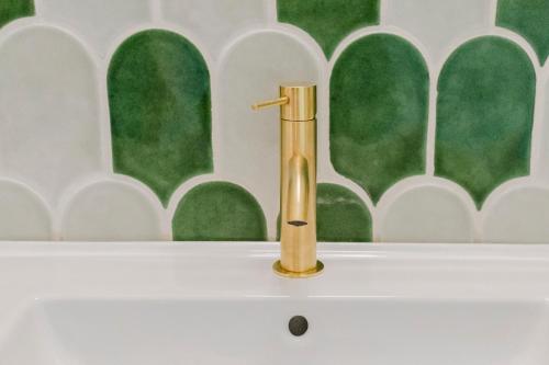 a gold faucet on top of a white sink at La casa di rovere in Lugo
