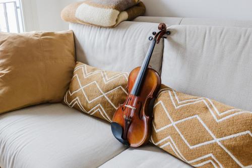 a violin sitting on a white couch with pillows at La casa di rovere in Lugo