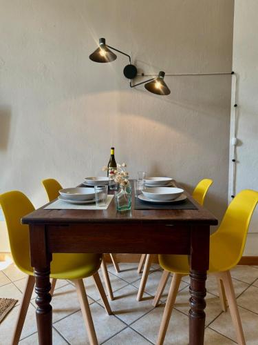 a dining room table with yellow chairs and a bottle of wine at BALCONCINI VISTA TORRI - comfort nel centro storico in Savigliano
