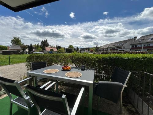 a table with chairs and a bowl of fruit on it at Gemütliches 2-Zimmer-Apartment im Fichtelgebirge - nahe der Skipiste mit Terrasse & Free Parking in Mehlmeisel