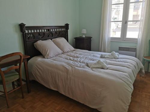 - une chambre dotée d'un grand lit avec des draps blancs et une chaise dans l'établissement Chez Anna, à Concarneau