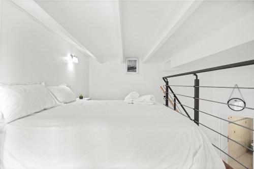 - un lit blanc dans une chambre blanche avec une horloge dans l'établissement 3 bd carnot cannes, à Cannes