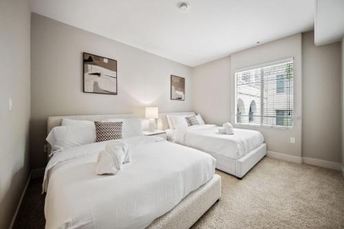 a white bedroom with two beds and a window at Promo Casa Miel Heart of Westwood Luxury Condo in Los Angeles