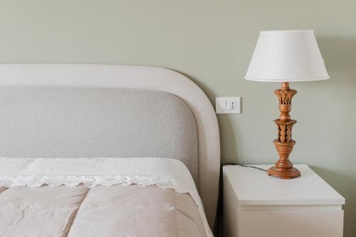 a bed with a nightstand with a lamp on it at La casa di rovere in Lugo