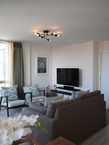 a living room with couches and a flat screen tv at Spacious seaside apartment with terrace, Kemptown in Brighton & Hove