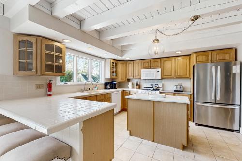 a kitchen with wooden cabinets and a stainless steel refrigerator at #OB Pool House in Oak Bluffs