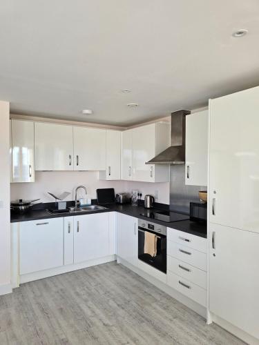 a kitchen with white cabinets and black counter tops at Spacious seaside apartment with terrace, Kemptown in Brighton & Hove