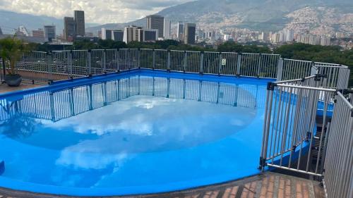 a large blue swimming pool with a city in the background at Pie de Cerro Condominium in Medellín