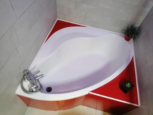 une baignoire blanche dans une salle de bain avec des armoires rouges dans l'établissement Maison de ville dans écrin de verdure, à Nîmes