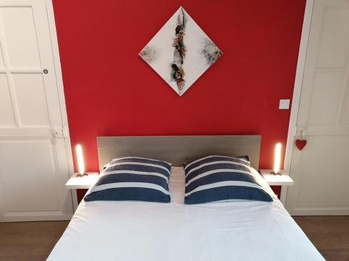 une chambre avec un mur rouge et un lit avec deux oreillers dans l'établissement Maison de ville dans écrin de verdure, à Nîmes