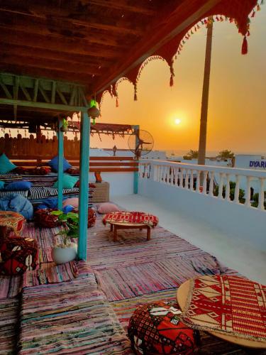a balcony with pillows and a sunset in the background at Ghazala Oasis Hotel in Dahab