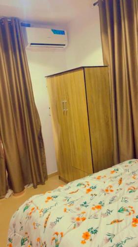 a bedroom with a bed and a wooden cabinet at EMERALD - Live and chill in Ibadan