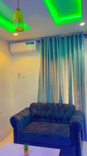 a living room with a blue couch in front of a curtain at EMERALD - Live and chill in Ibadan