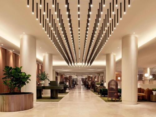 a hotel lobby with a large chandelier hanging from the ceiling at Sofitel Sydney Wentworth in Sydney