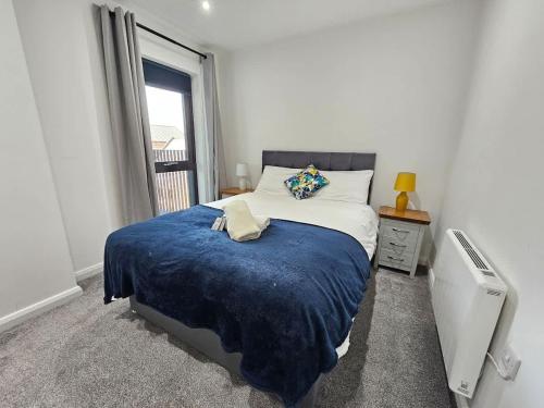 a bedroom with a bed with a blue blanket and a window at 2 BR City Centre Apartment with Terrace in Belfast