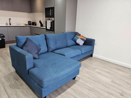 a blue couch in a living room with a kitchen at 2 BR City Centre Apartment with Terrace in Belfast
