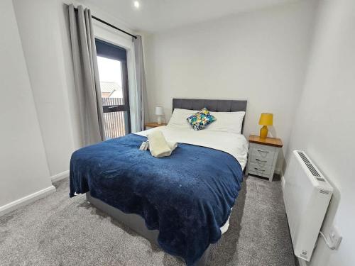 a bedroom with a bed with a blue blanket and a window at 2 BR City Centre Apartment with Terrace in Belfast