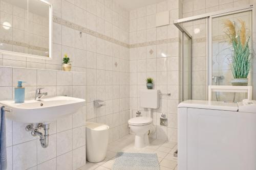 a white bathroom with a sink and a toilet at Ferienwohnung Sonnenplatz Moba-Travel in Travemünde