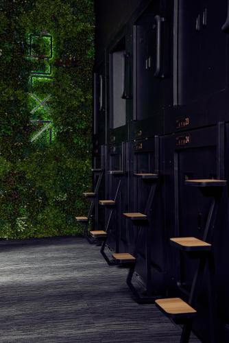 a row of benches in front of a green wall at Capsule Hotel Montreal in Montréal