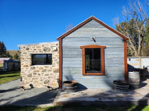 a small building with a window and some barrels at The Good Shepherds Hut in the NZ Dark Sky Reserve in Simons Pass