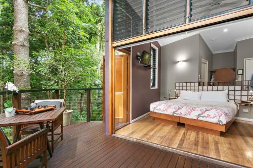 1 dormitorio con 1 cama y una mesa en la terraza en Azabu Retreat & Spa, en Byron Bay