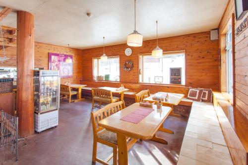 a dining room with wooden walls and tables and chairs at Green Grass Hakuba in Hakuba