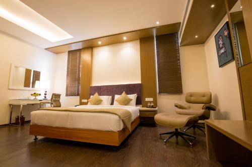 a bedroom with a bed and a desk and chairs at Kiscol Grands Hotel in Coimbatore