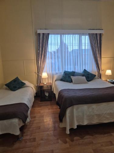 Dos camas en una habitación con ventana. en alojamiento en punta arenas, en Punta Arenas