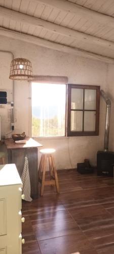 een keuken met een tafel en een kruk in een kamer bij La calendula eco cabaña in Los Hornillos