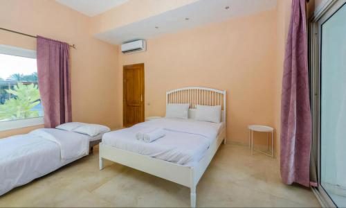 two beds in a room with a window at Modern Villas in White Villas, El Gouna in Hurghada