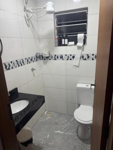 une salle de bain avec toilettes, lavabo et miroir dans l'établissement Casa Raio de Luz, à Itanhaém
