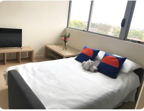 a teddy bear sitting on a bed in a bedroom at Modern 2BR Apartment in Sydney